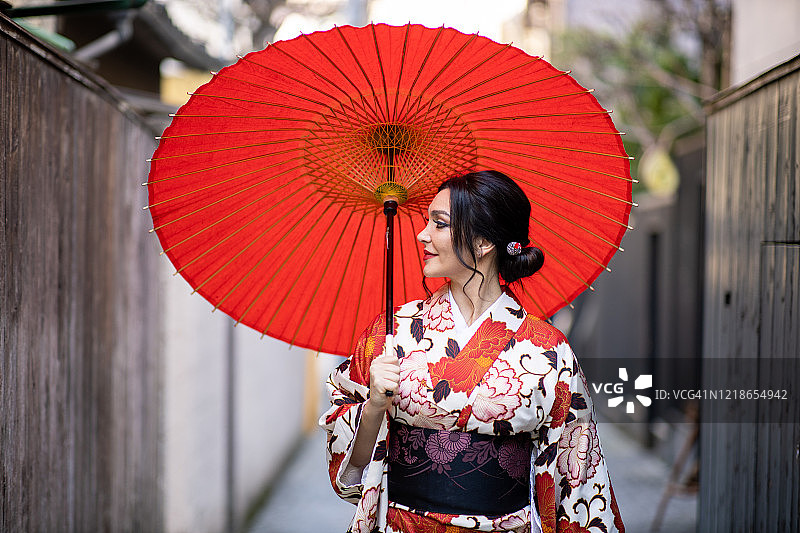 穿着和服的白人妇女走在日本传统的狭窄街道上图片素材