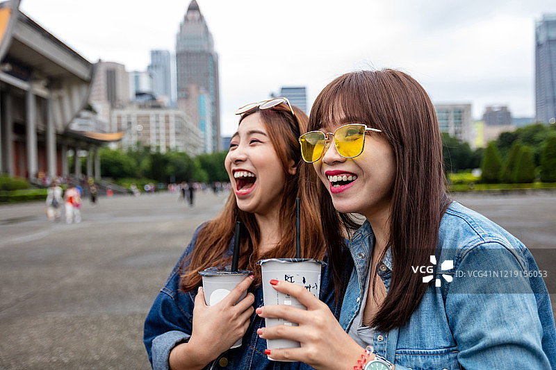两个年轻女人拿着一次性杯子在城市里图片素材