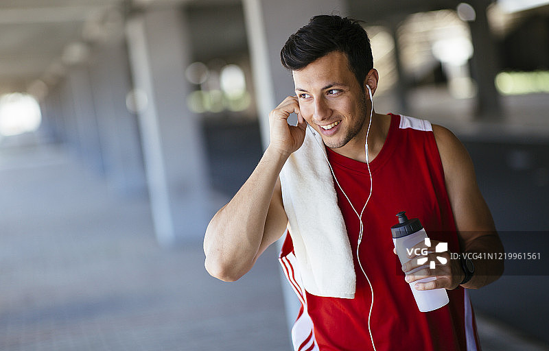 微笑的运动员听音乐，跑步锻炼后休息图片素材