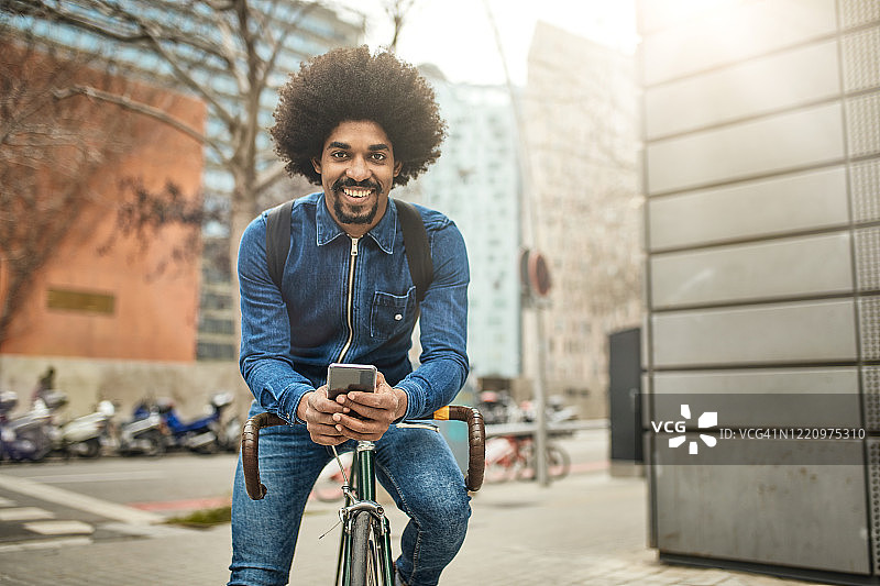 微笑32岁的城市自行车使用智能手机图片素材