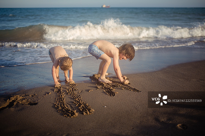 兄弟们在海边一起玩沙子图片素材