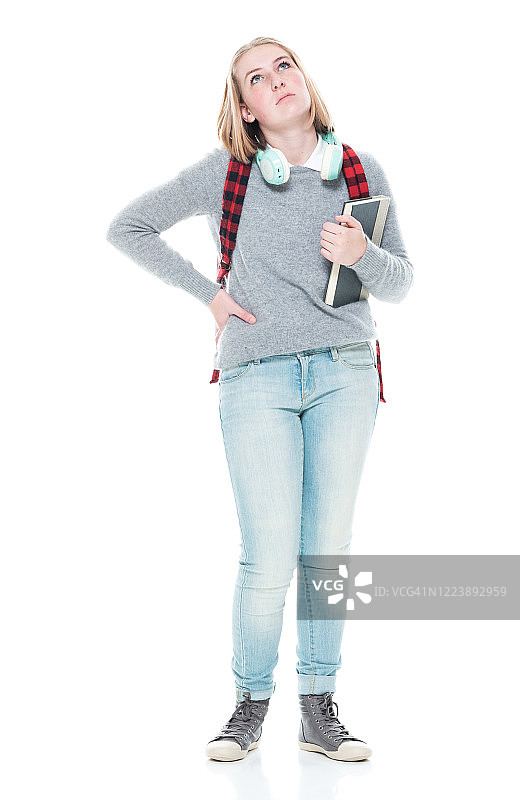 z一代的少女高中生穿着毛衣、拿着书、戴着耳机站在白色背景前图片素材