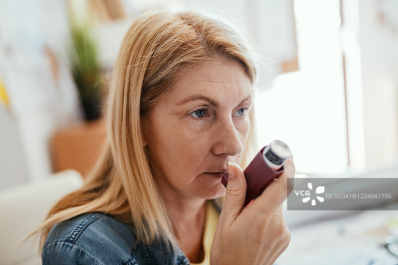 成年女性在家工作，使用哮喘吸入器图片素材