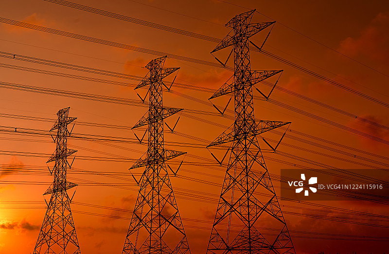 高压塔和电线与日落的天空。电力波兰人。动力和能源概念。高压电网塔架带电线电缆。美丽的橙红色日落天空。基础设施。图片素材