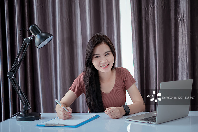 亚洲女性视频会议用户界面与笔记本电脑在家远程工作社交距离防止冠状病毒与互联网视频通话技术讨论业务时隔离。图片素材
