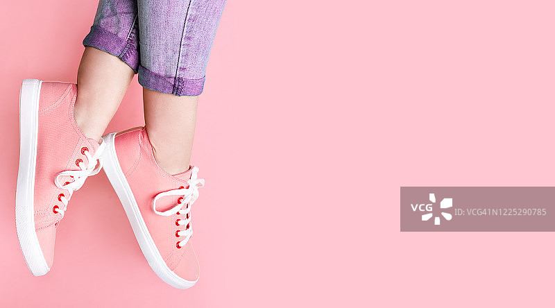 女人在时尚运动鞋近彩色墙，特写。空间的文本图片素材