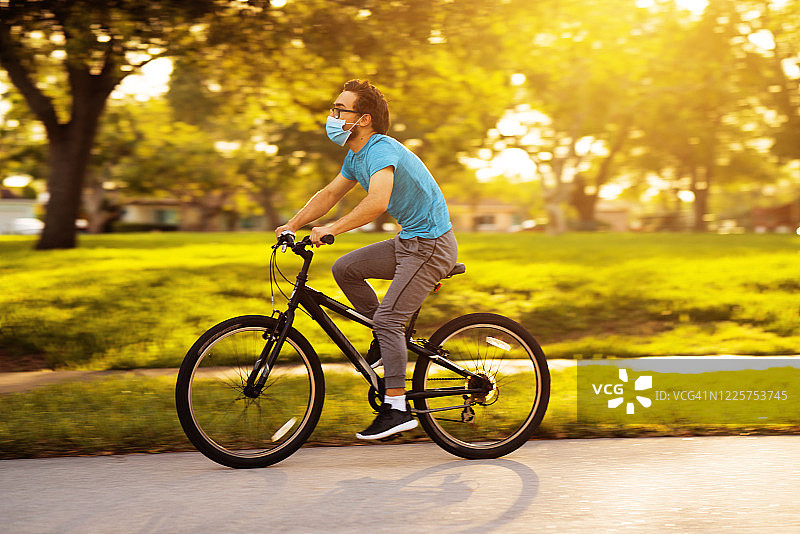 戴着面具在附近骑自行车的青少年图片素材