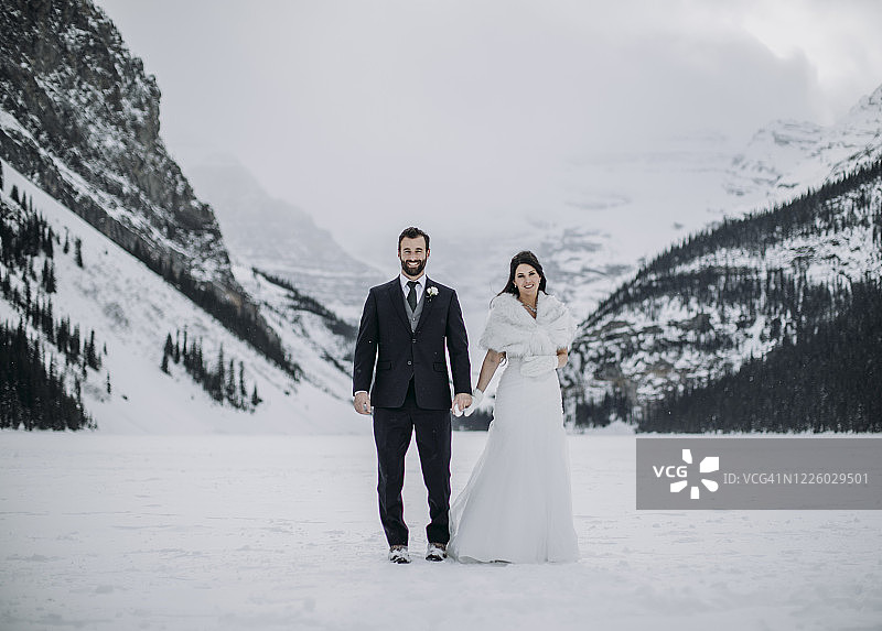 加拿大阿尔伯塔省，一对新婚夫妇站在结冰的路易斯湖上图片素材