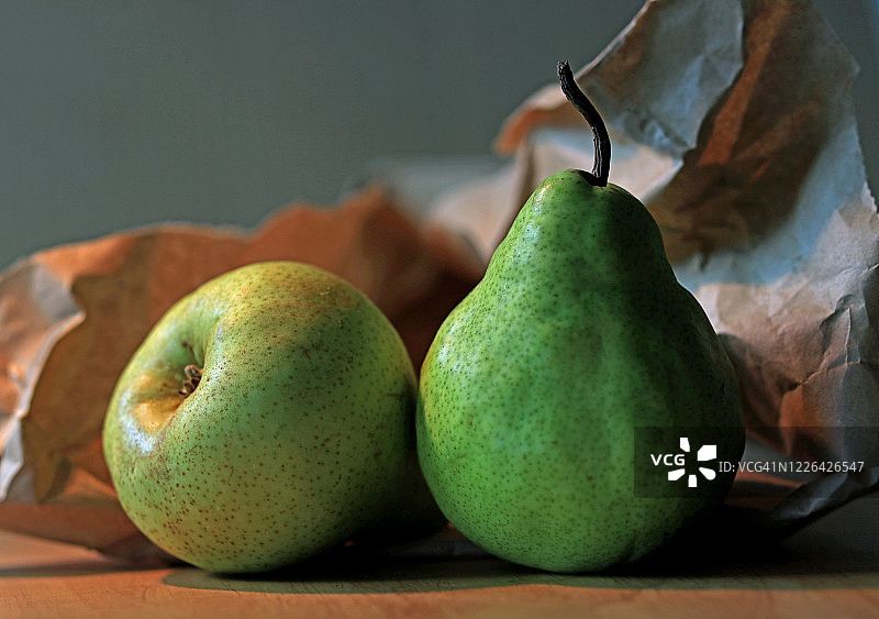 两颗熟透的梨，背景是皱巴巴的棕色纸袋图片素材