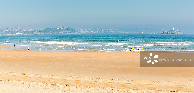 海滩上冲浪者的全景，以桑坦德市为背景图片素材