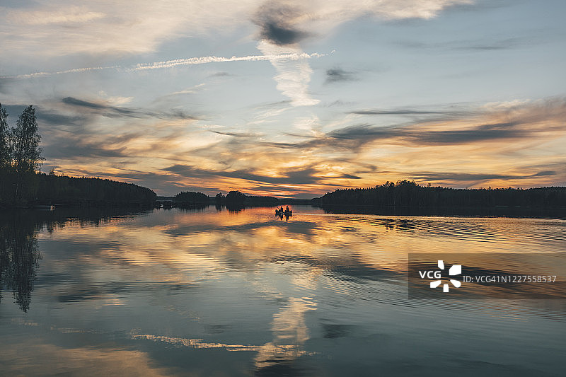 日落时，年轻人在湖上划船图片素材