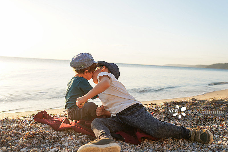 可爱的男孩和妹妹坐在沙滩上玩耍图片素材