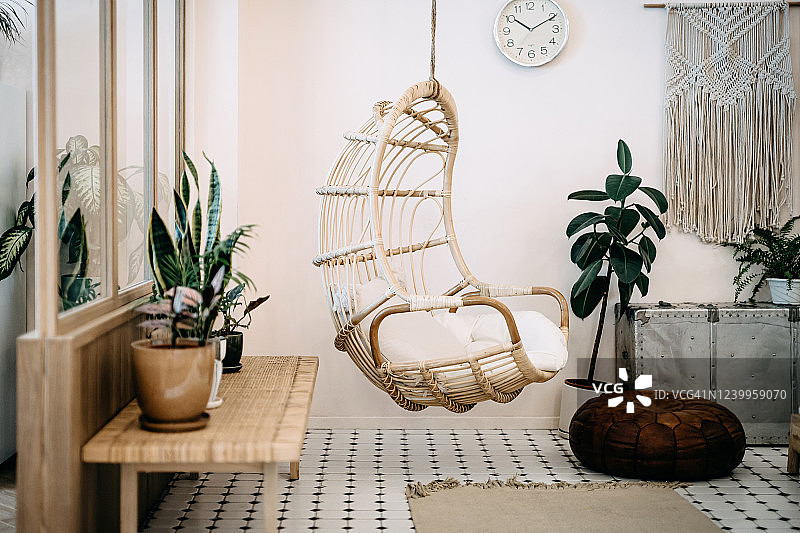 舒适的吊椅在阁楼客厅与时尚和波西米亚设计。精心设计，用各种有趣的植物装饰图片素材