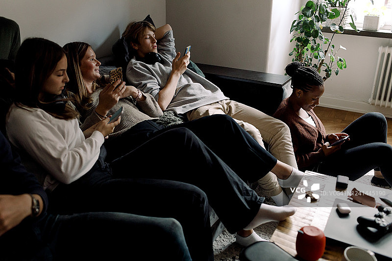 青少年朋友坐在家里用智能手机使用社交媒体图片素材