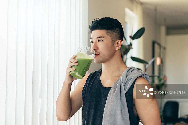 自信的亚洲男人在锻炼后喝蛋白质奶昔图片素材