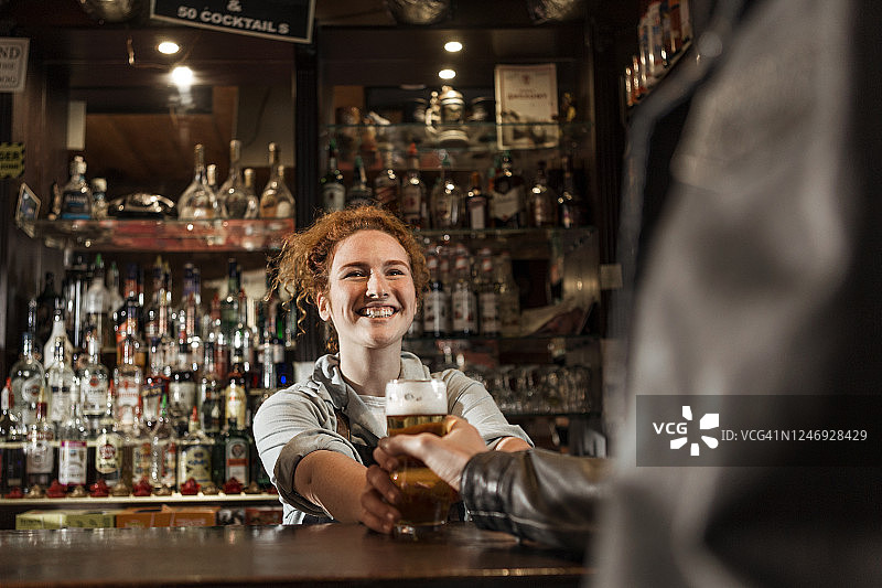 微笑的女调酒师提供啤酒图片素材