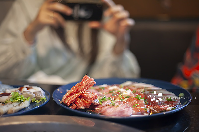 一个女人在餐厅用手机拍食物照片图片素材
