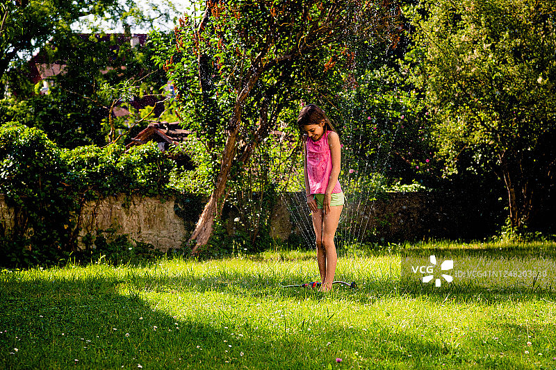 小女孩在玩花园里的洒水器图片素材