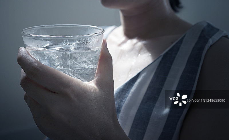 在炎热的季节里，握住女性口渴的手，握着新鲜的水和冰块饮用图片素材