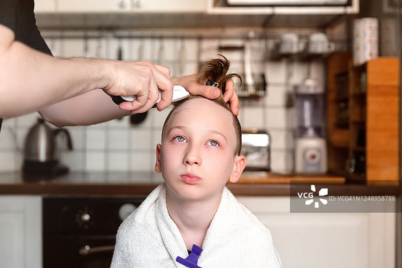 可爱的小男孩正在被他的父亲剪头发图片素材
