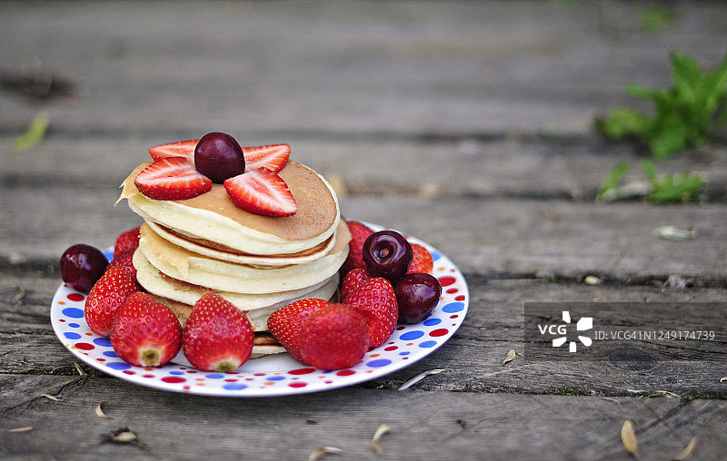 早餐在自然界中。草莓樱桃煎饼，美丽的木头背景。健康美味的食物图片素材