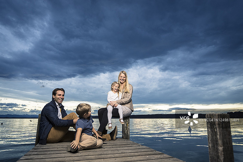 整个幸福的家庭坐在斯塔恩伯格的码头上看着乌云密布的天空图片素材