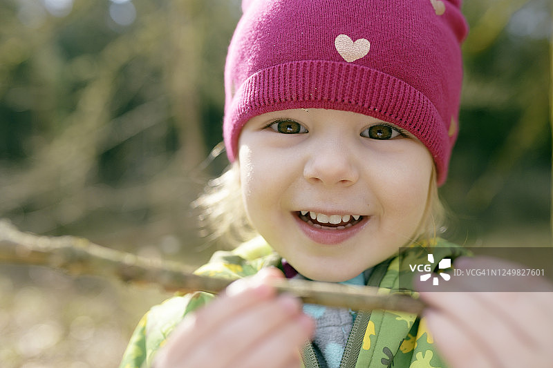 微笑的小女孩的肖像与树枝在自然界图片素材