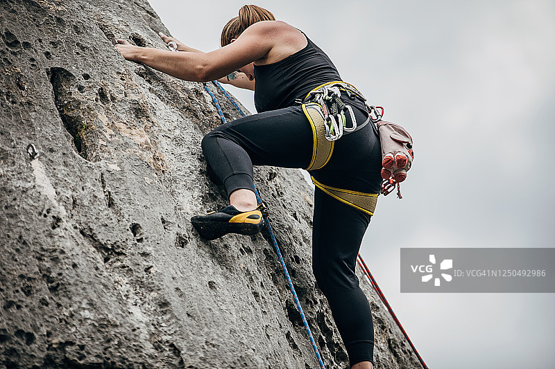 一个运动的年轻女子正在攀登岩石图片素材