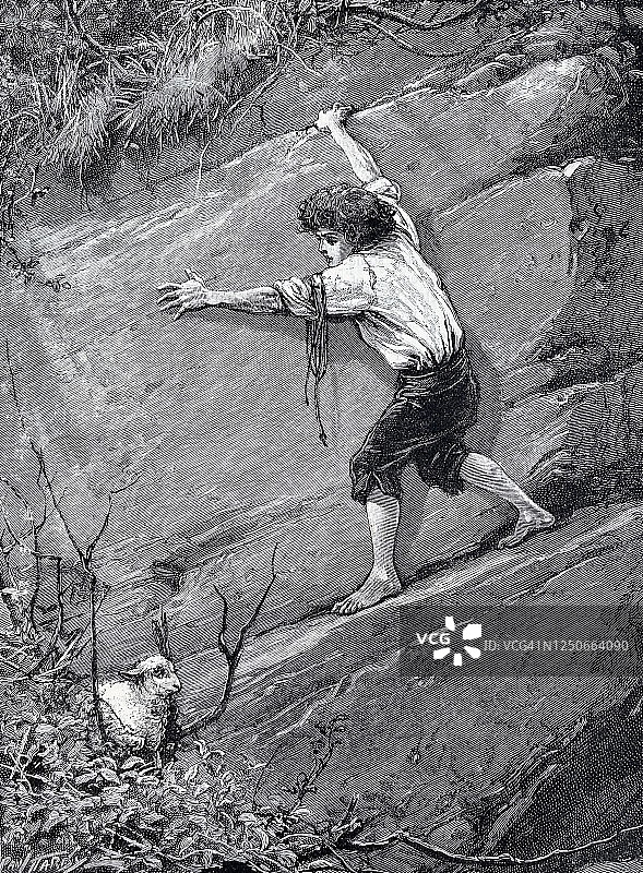 一名男子试图在岩壁上救一只羔羊图片素材
