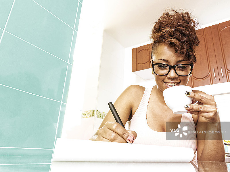 启发黑人妇女在记事本上写字，同时享受一杯咖啡微笑图片素材