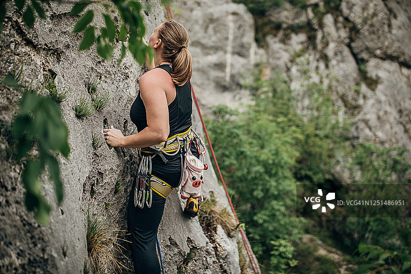年轻的女运动员正在攀登岩石图片素材