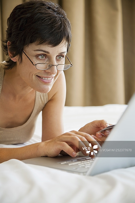女人在床上用信用卡和笔记本电脑网上购物图片素材