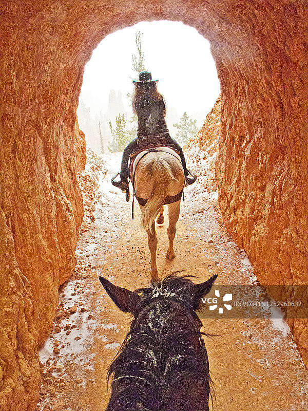 马和一个女牛仔骑手在犹他州布莱斯峡谷峡谷隧道进入春季暴风雪-系列的一部分图片素材