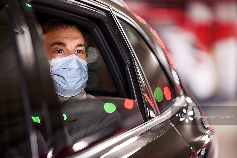 在新冠肺炎疫情爆发期间，一名公司领导戴着防护口罩在开车时打电话图片素材