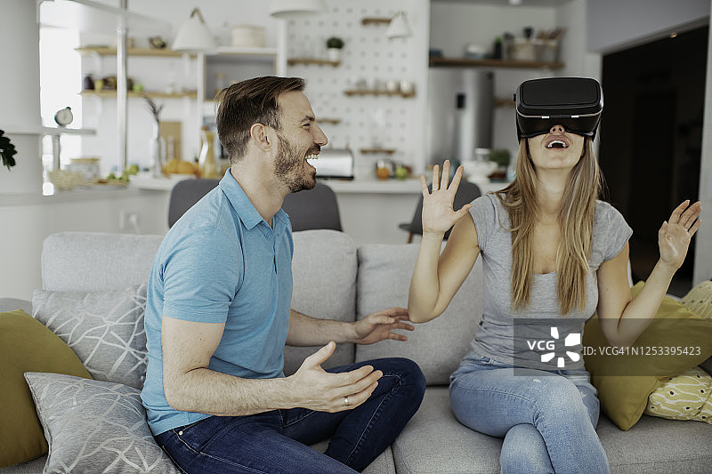 快乐的夫妇在客厅里玩虚拟现实眼镜。图片素材