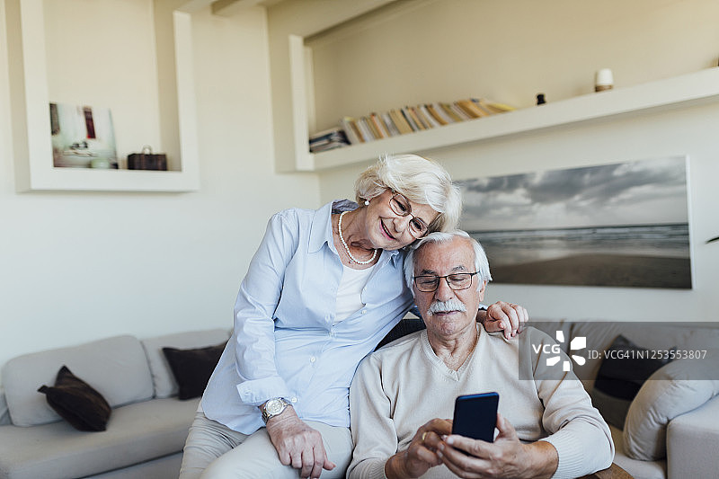上了年纪的情侣通过智能手机和朋友聊天图片素材