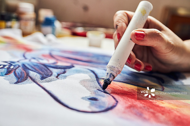 女艺术家用蓝色马克笔在t恤上画画图片素材