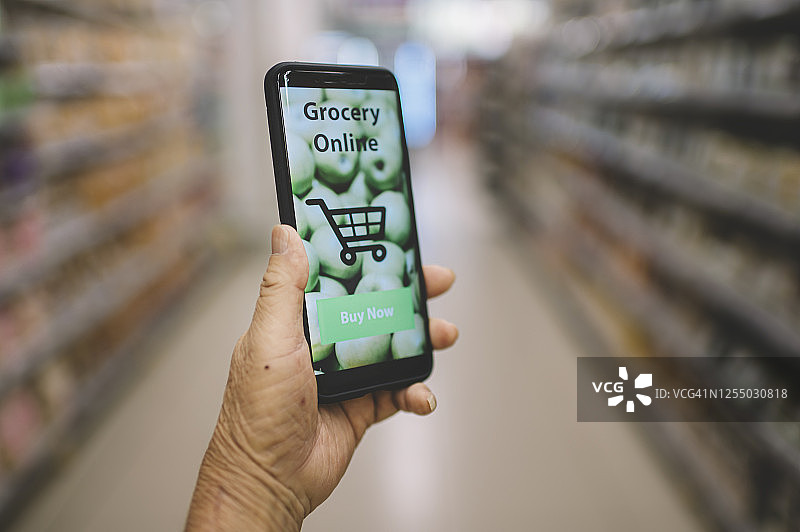 手机屏幕上模糊超市背景的手握在线购物手机应用程序图片素材