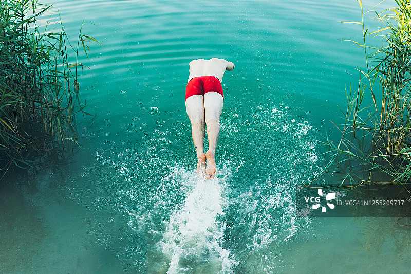 年轻人在夏天跳进绿松石色的湖里图片素材