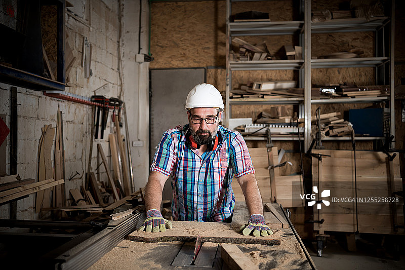 木工在车间从事木材工艺生产建筑材料或木制家具的木匠。成熟的木匠使用专业工具进行制作。DIY工匠和木工概念。图片素材