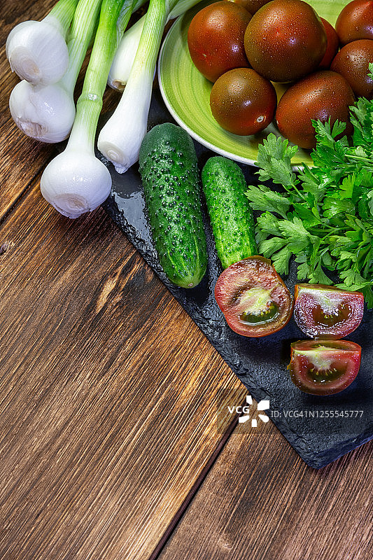 绿色的新鲜洗过的湿蔬菜放在一张桌子上，有一个复制空间，健康饮食天然食品和维生素素食有机食品西红柿，洋葱，韭菜黄瓜欧芹图片素材