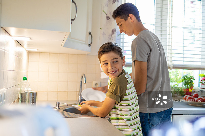 两个男孩在厨房水槽里洗盘子图片素材