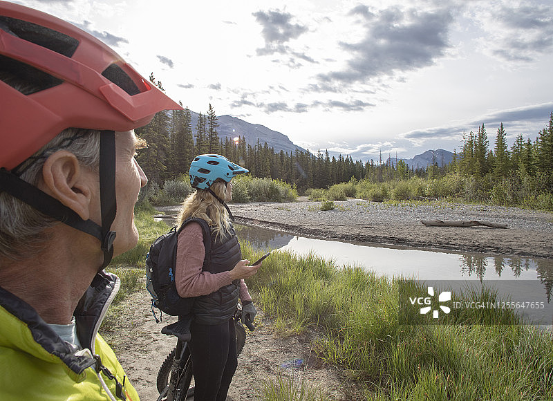 一对夫妇骑着山地电动自行车在湖边放松图片素材