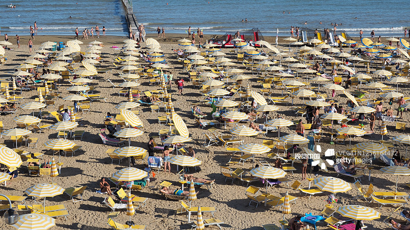 Jesolo,意大利。意大利沙滩上的沙滩伞和日光浴床。旺季，很多人又很多乱。亚得里亚海海岸。黄白伞图片素材