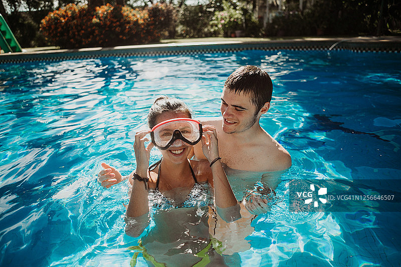 年轻的青少年夫妇在夏天的时候在游泳池的水里玩图片素材