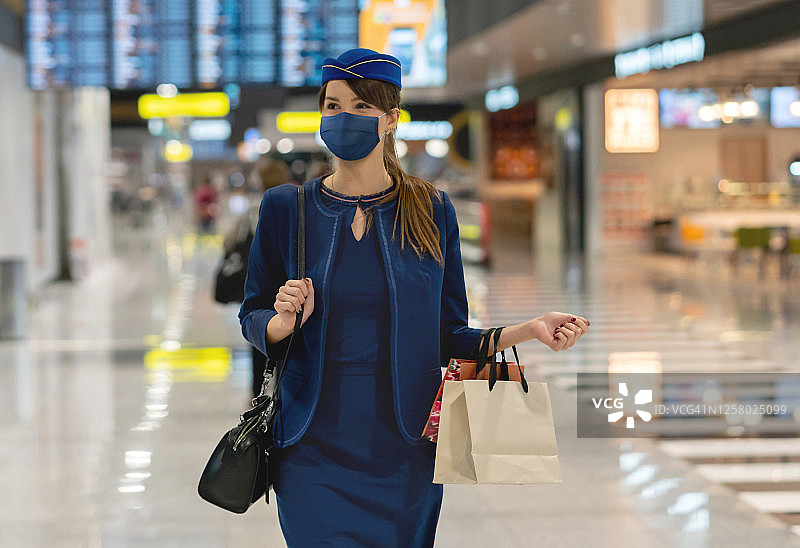 空乘人员在机场戴着口罩，携带免税商品图片素材