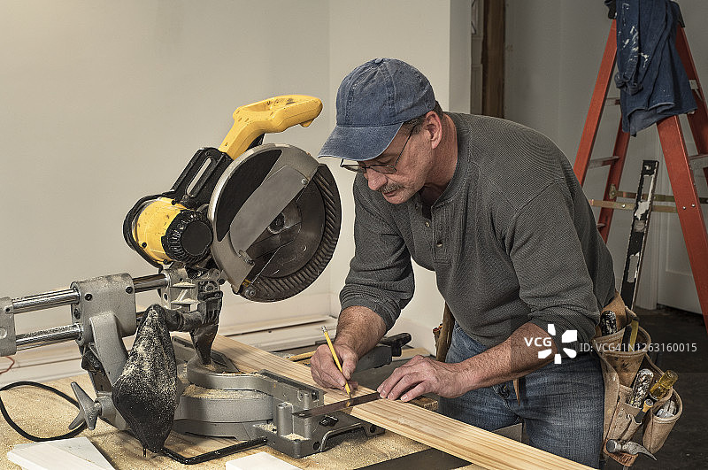 男木匠在房屋建筑工地上用锯子在木板上划线图片素材
