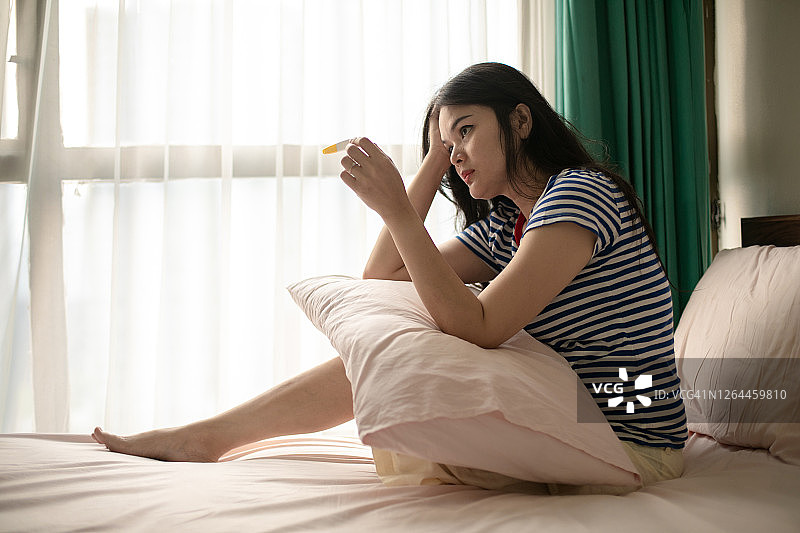 亚洲年轻女子看着怀孕测试失望的表情图片素材