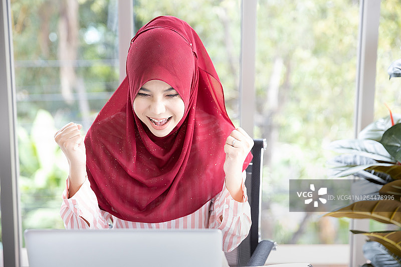 兴奋的亚洲穆斯林商业妇女笔记本电脑。图片素材
