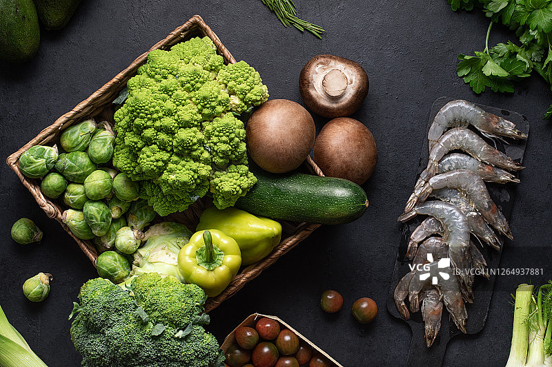 绿色蔬菜和虾，食物背景。黑色餐桌上新鲜有机产品的健康饮食理念图片素材